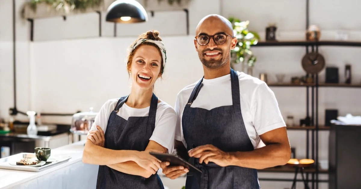 Two hospitality team members in aprons ready to welcome guests at a Malta restaurant